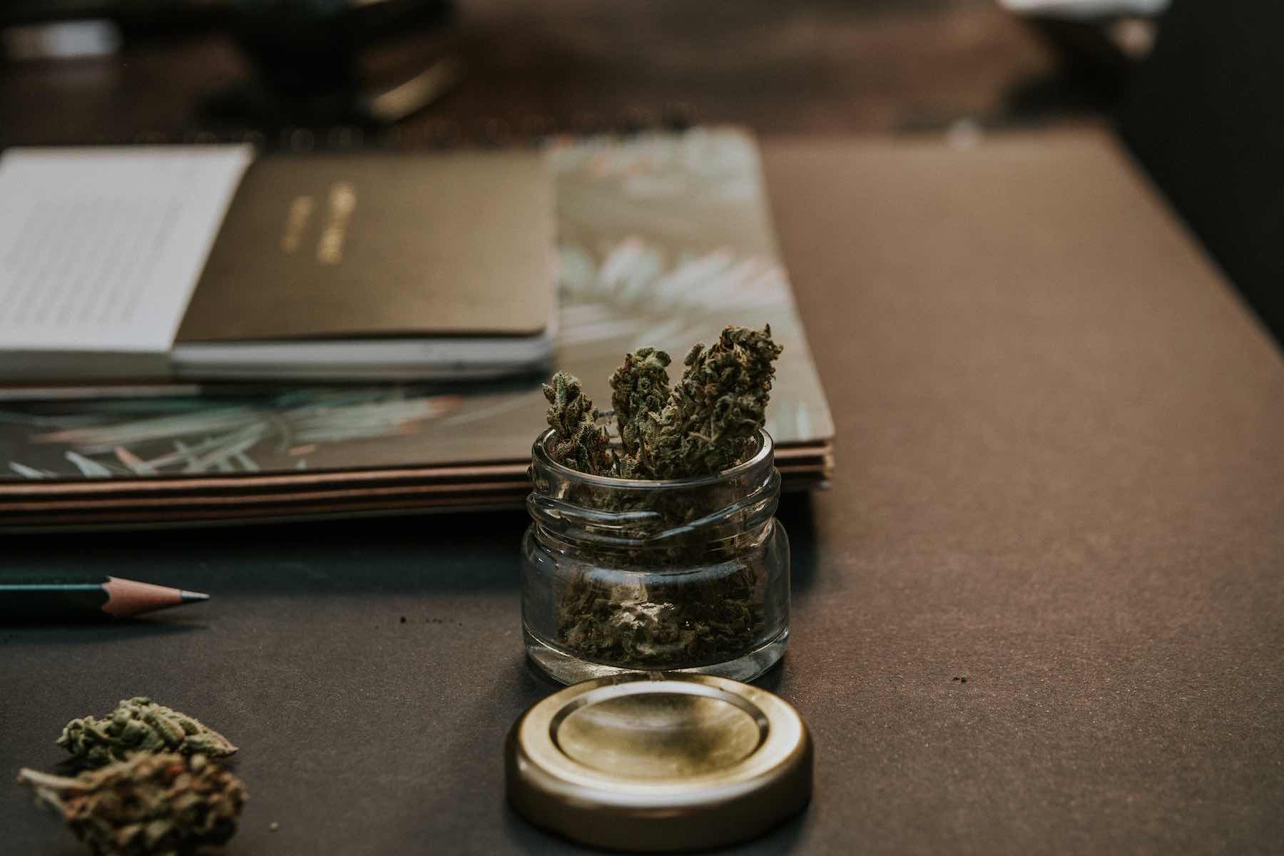 HHC soll Verboten werden Ein Glas mit CBD Blüten auf einem Tisch