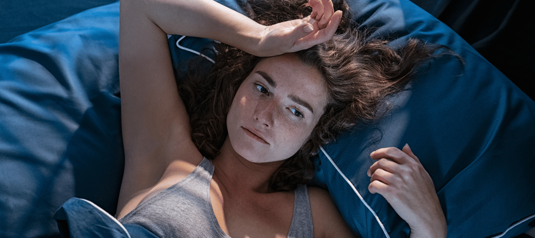 Schlaflosigkeit: Wie CBD Blüten Ihnen zu einem besseren Schlaf verhelfen Eine Frau mit Schlafstörung die im Bett liegt