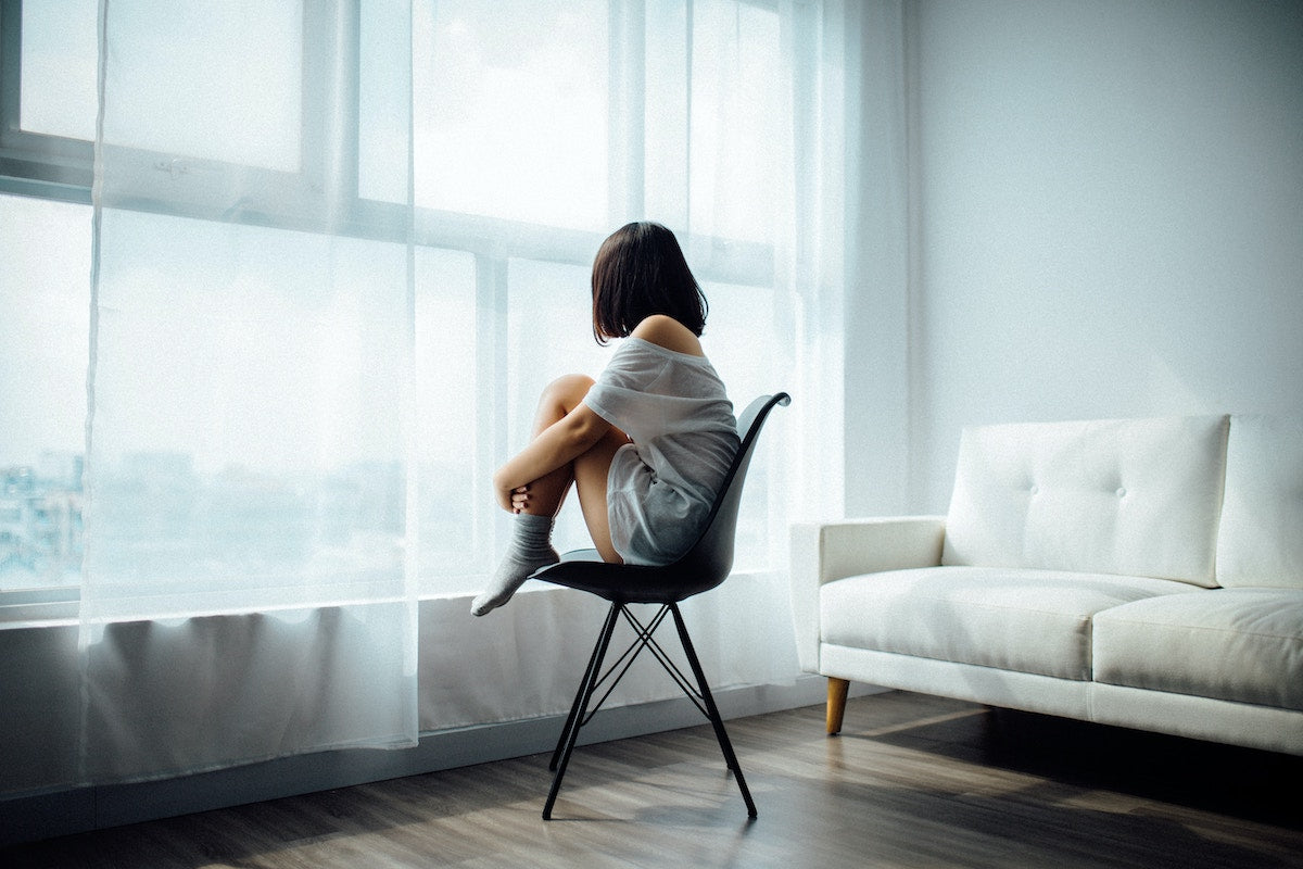CBD und 1D-LSD: Neue Perspektiven in der Behandlung von Depressionen Frau die depressiv ist sitzt auf einem Stuhl und guckt aus dem Fenster raus