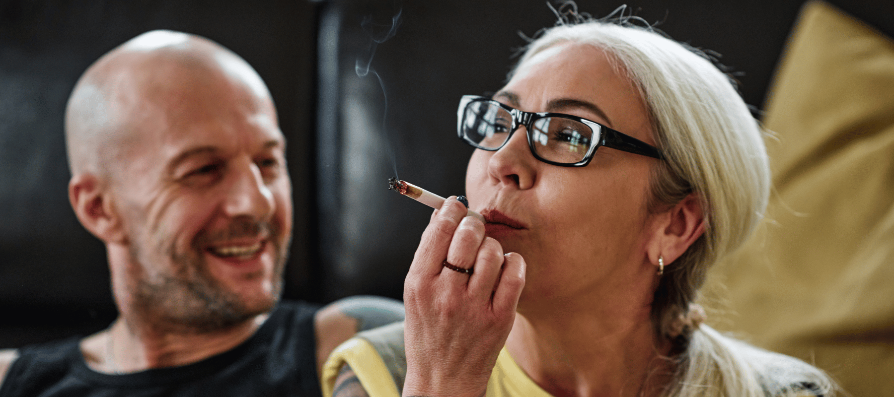 Wo darf ich in Deutschland kiffen? Legal Cannabis konsumieren an beliebten Orten 2024 Eine Frau die an ein Cannabis Joint zieht und ein Mann mit Glatze der sie anlächelt