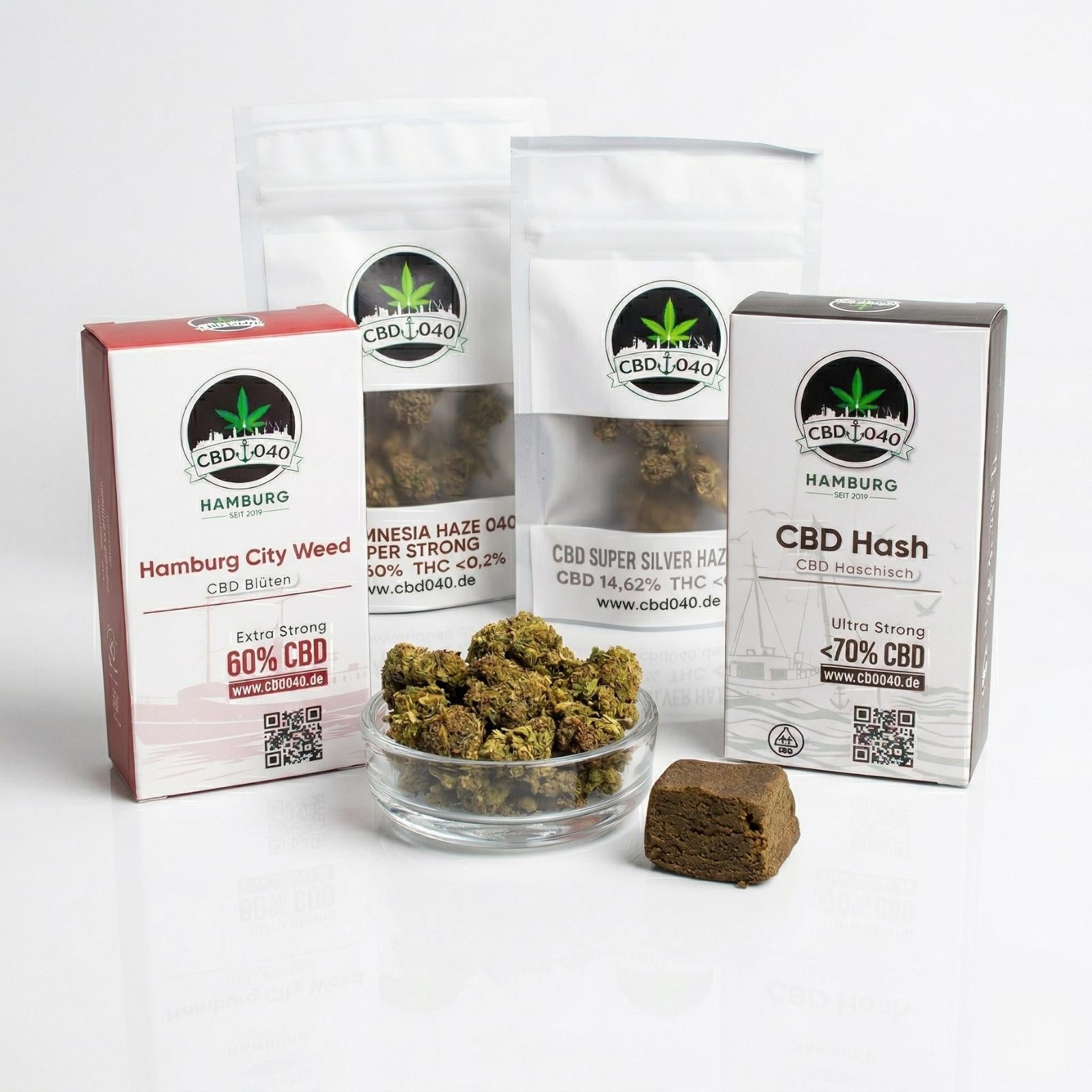 Professionelles Studiofoto des CBD040 Hamburg Premium CBD Produkt-Sets auf weißem Hintergrund. Die Auswahl zeigt Hamburg City Weed Blüten (Extra Strong 60% CBD), Ultra Strong CBD Hash Haschisch (<70% CBD) sowie Amnesia Haze und Super Silver Haze Beutel. Im Vordergrund stehen eine Glasschale mit getrockneten CBD Blüten und ein Haschisch-Block. Professionelles Studiofoto des CBD040 Hamburg Premium CBD Produkt-Sets auf weißem Hintergrund. Die Auswahl zeigt Hamburg City Weed Blüten (Extra Strong 60% CBD), Ultra Strong CBD Hash Haschisch (<70% CBD) sowie Amnesia Haze und Super Silver Haze Beutel. Im Vordergrund stehen eine Glasschale mit getrockneten CBD Blüten und ein Haschisch-Block.